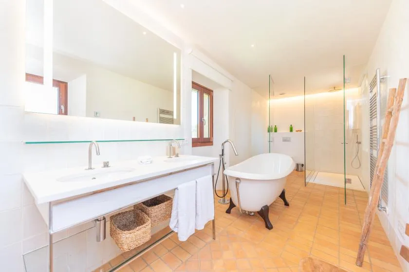 Un baño luminoso con un tocador largo y una bañera exenta.