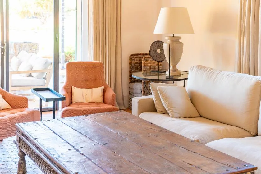 Una sala luminosa con asientos, una mesa de centro de madera y ventanales.
