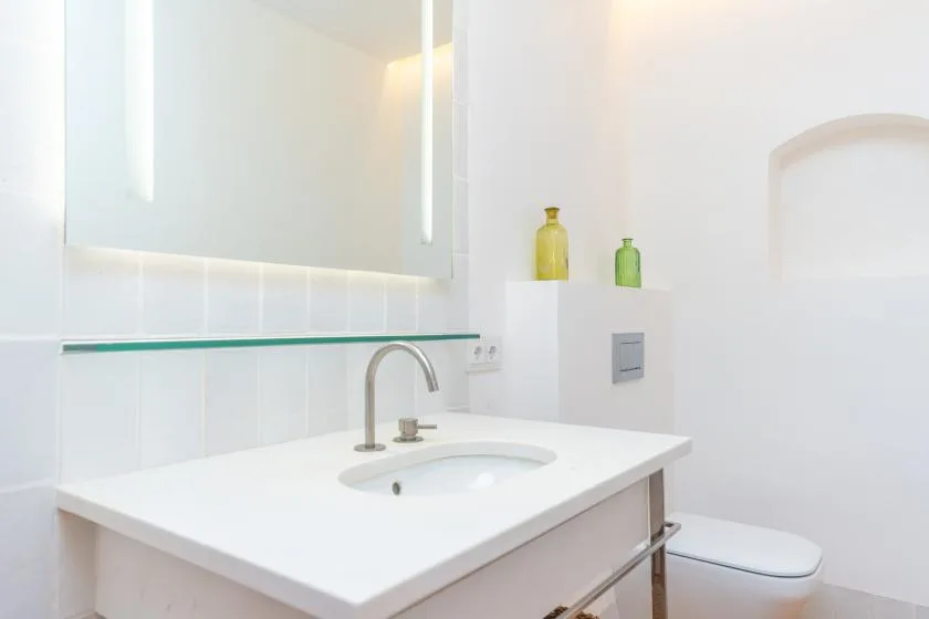 Un baño luminoso con lavabo blanco e inodoro.