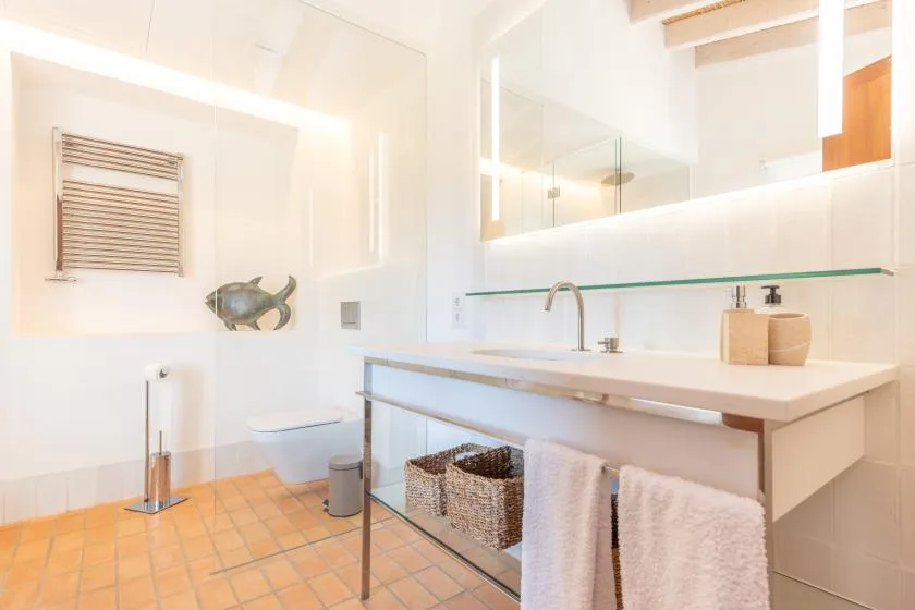 Un baño luminoso con lavabo, espejo y toallas blancas.