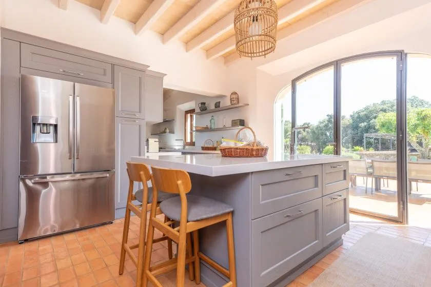 Una cocina luminosa con una isla grande y una puerta arqueada de vidrio que da a un patio.