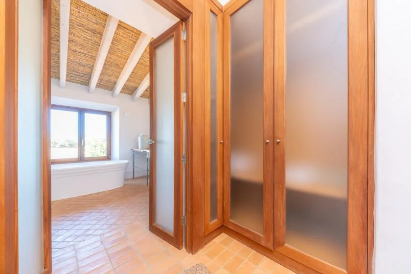 Un baño con bañera, ventana y puertas de vidrio esmerilado.