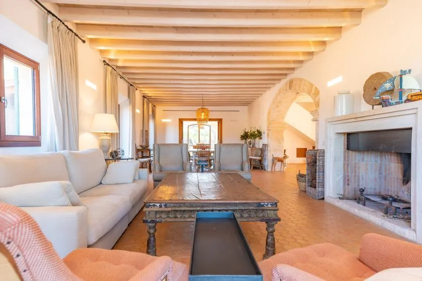 Una sala de estar luminosa con asientos alrededor de una mesa baja de madera y una chimenea.