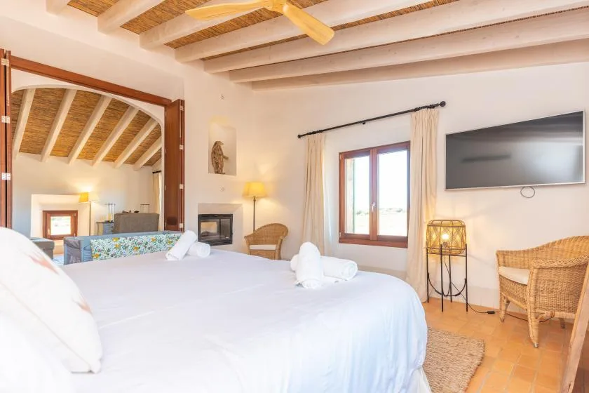 Un dormitorio con una cama grande, una ventana y un televisor en la pared.