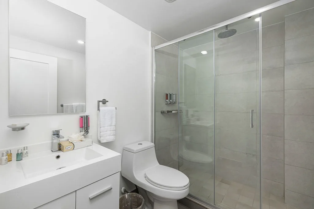 Step into your modern, pristine bathroom with a spacious walk-in shower, sleek vanity, and fresh towels ready for your stay.