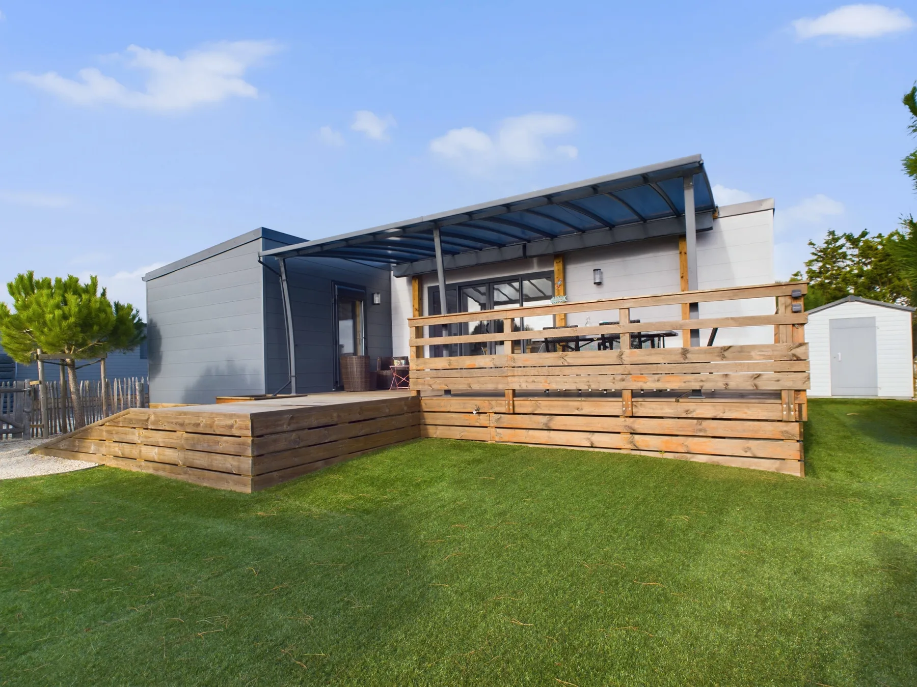 Modern chalet exterior with a covered wooden deck and lawn.