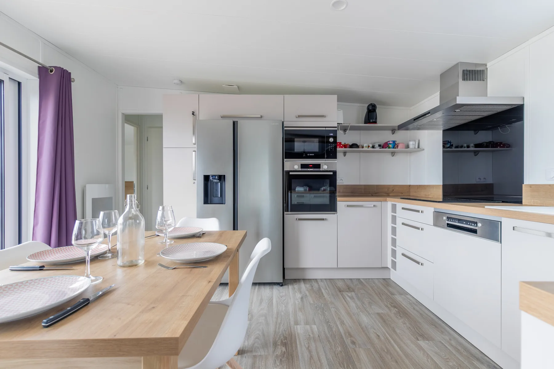 A modern kitchen with a dining table and built-in appliances.