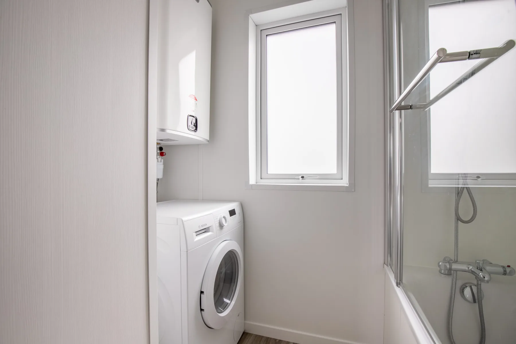 A compact laundry and shower room with a washing machine beside the shower.