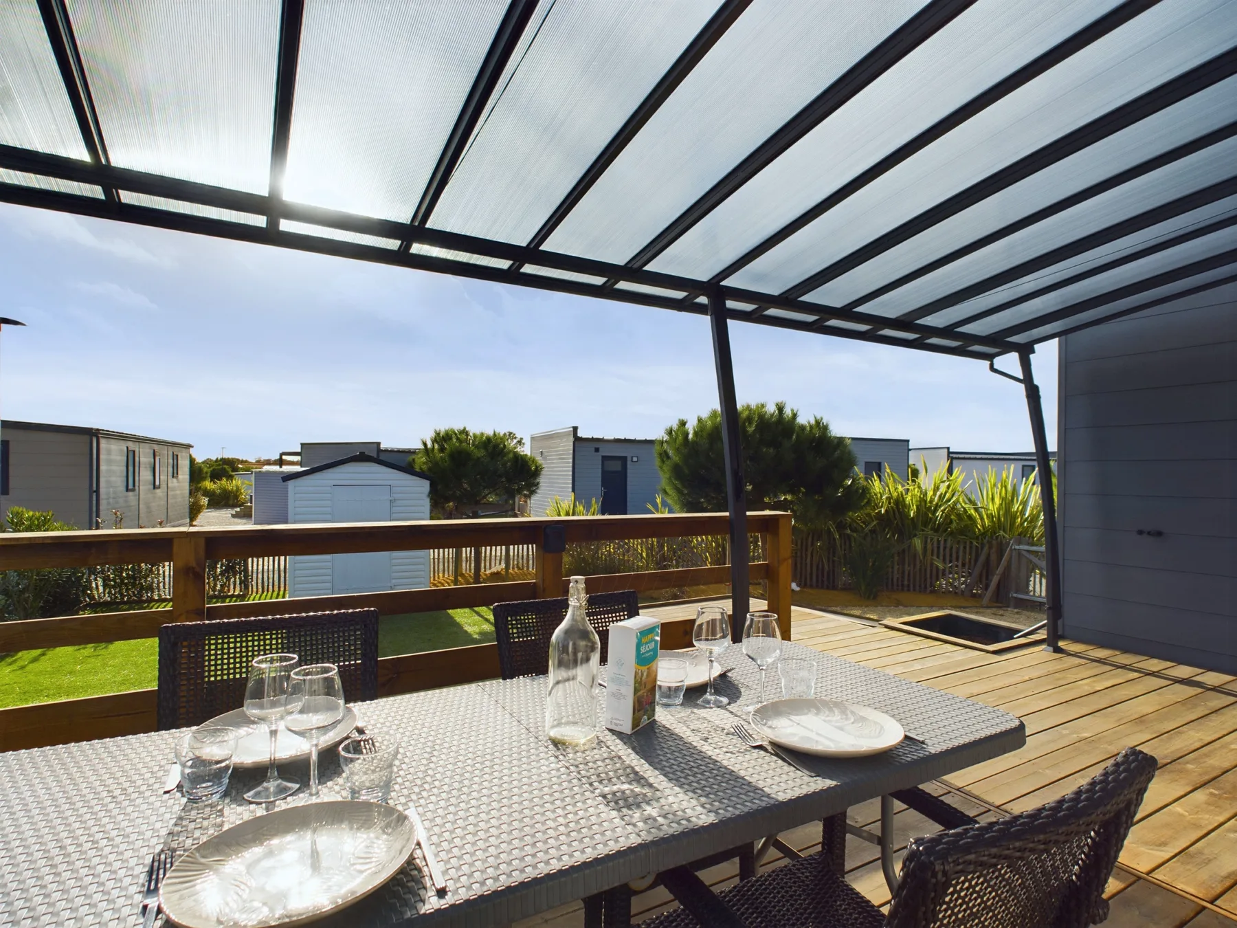 An outdoor dining area sits beneath a covered patio, overlooking nearby buildings.