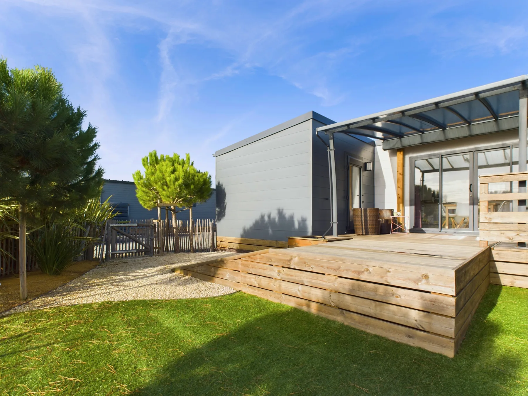 Modern house exterior with a raised wooden deck and lawn.