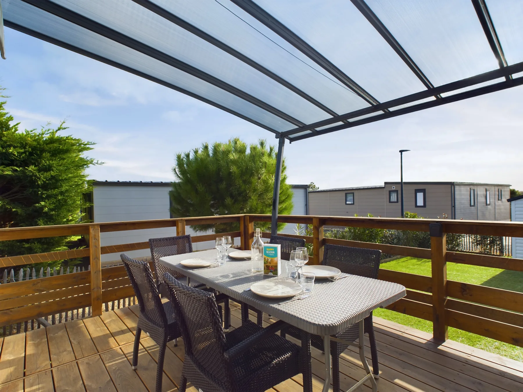 A covered outdoor dining area with a table and seating overlooks a grassy yard.