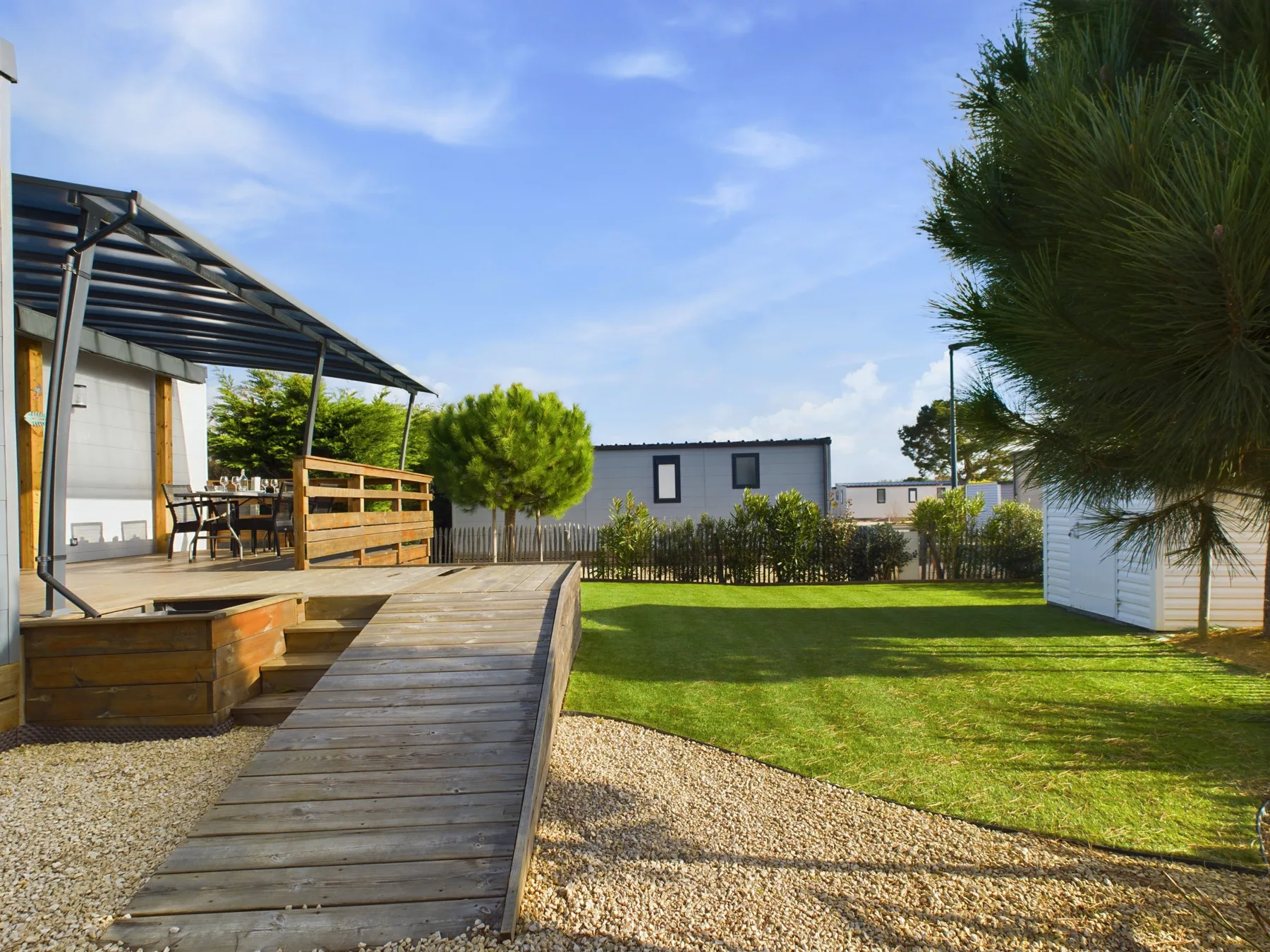 A chalet patio opens onto a grassy yard, with a wooden ramp beside the deck.