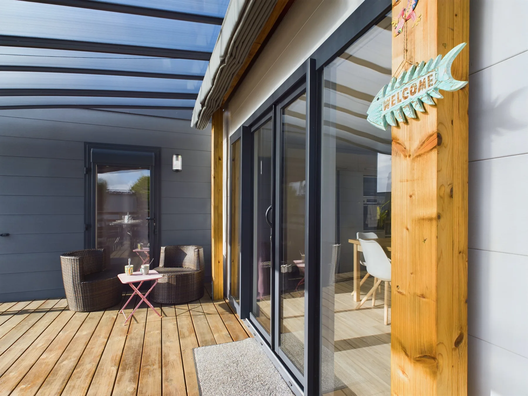 A wooden deck beside a modern building, with large glass doors and outdoor seating.