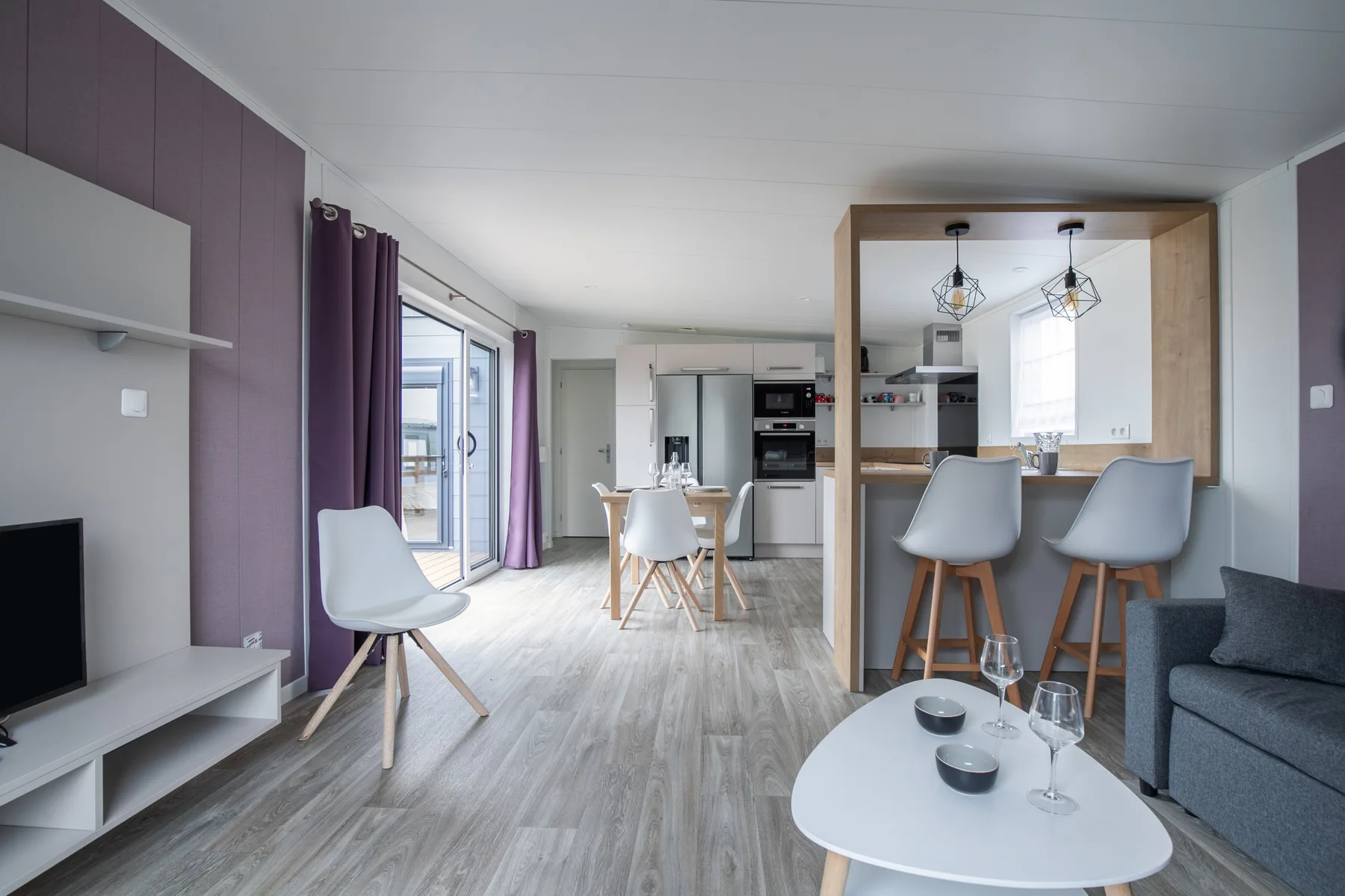 A bright open-plan living room with a dining table and kitchen counter.