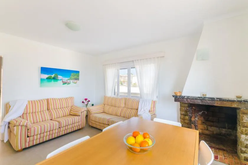 A bright living room with striped seating, a wooden table, and a fireplace.