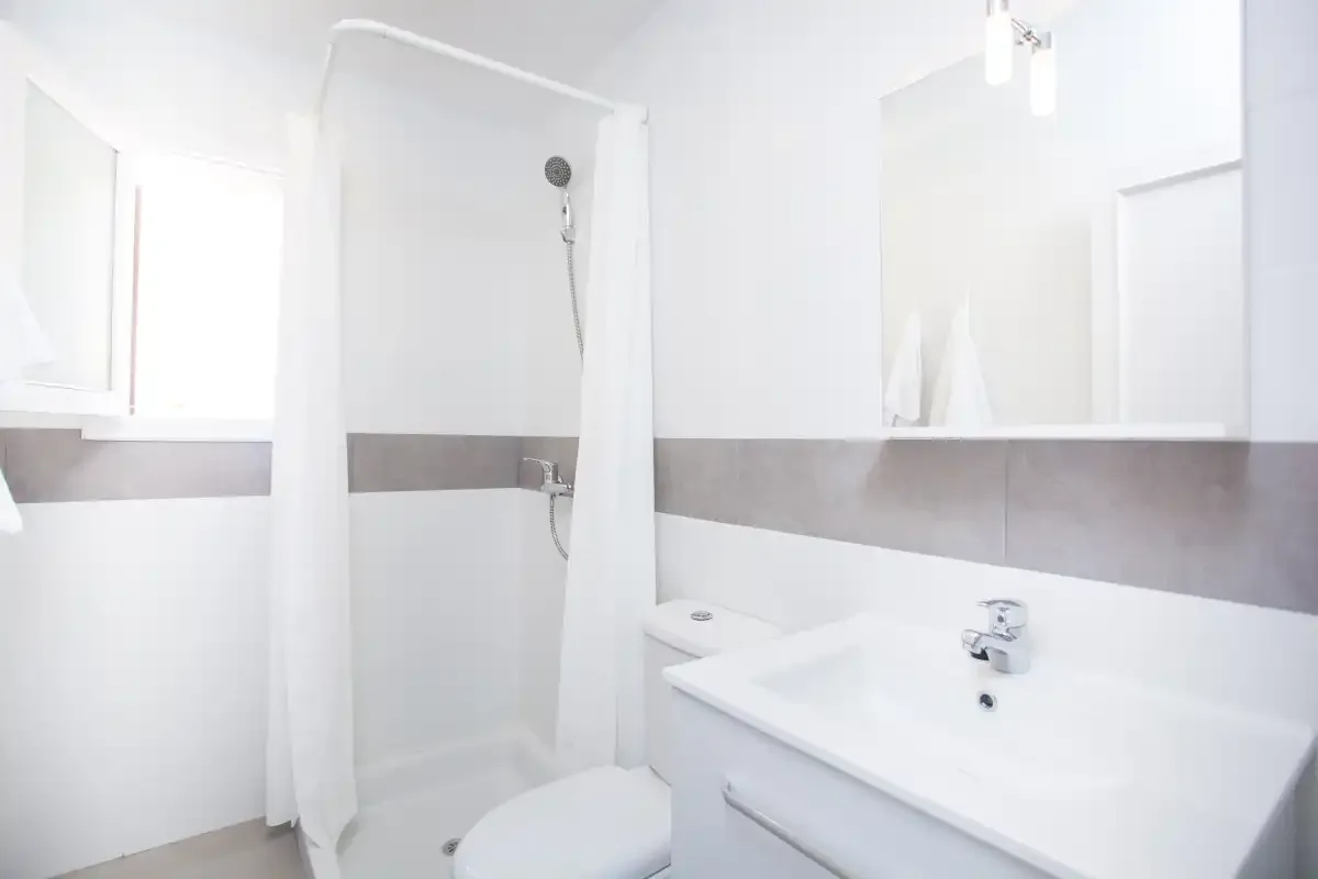 A bright bathroom with a shower and a white sink.