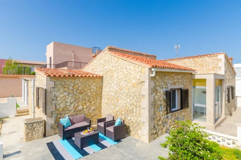 A stone house with an outdoor seating area beside the entrance.