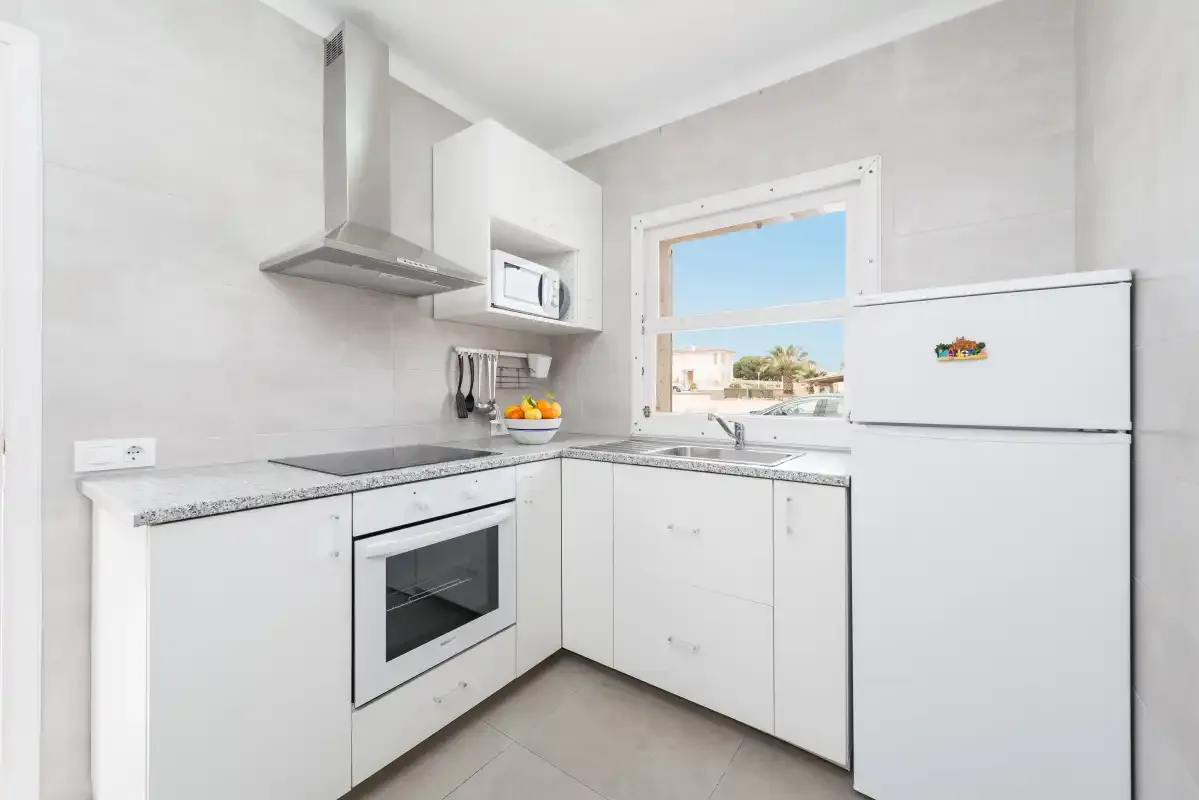 A bright white kitchen with a window above the sink.