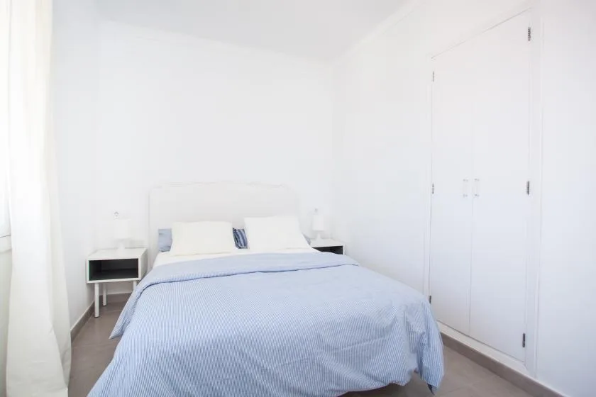 A bright bedroom with a bed dressed in pale blue bedding.