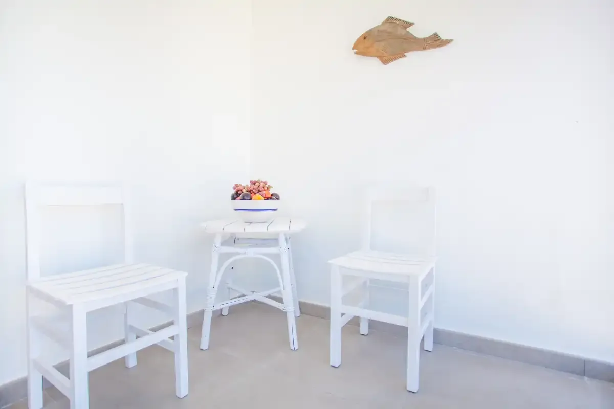 A bright seating area with two white chairs and a small table against a white wall.