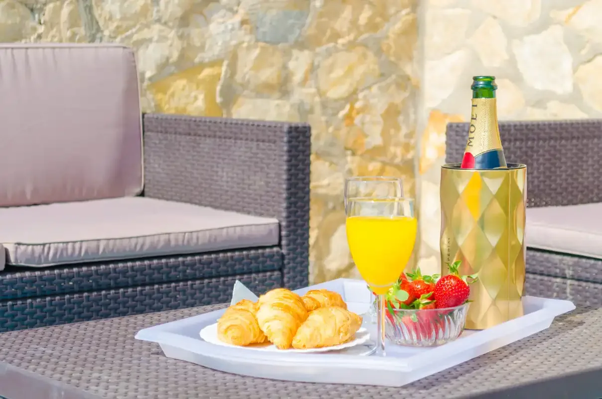 A breakfast tray with croissants, juice, and strawberries sits on outdoor seating.