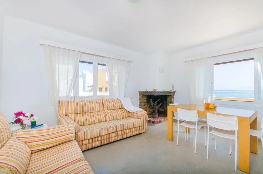 A bright living room has striped seating, a fireplace, and a dining table by the window.