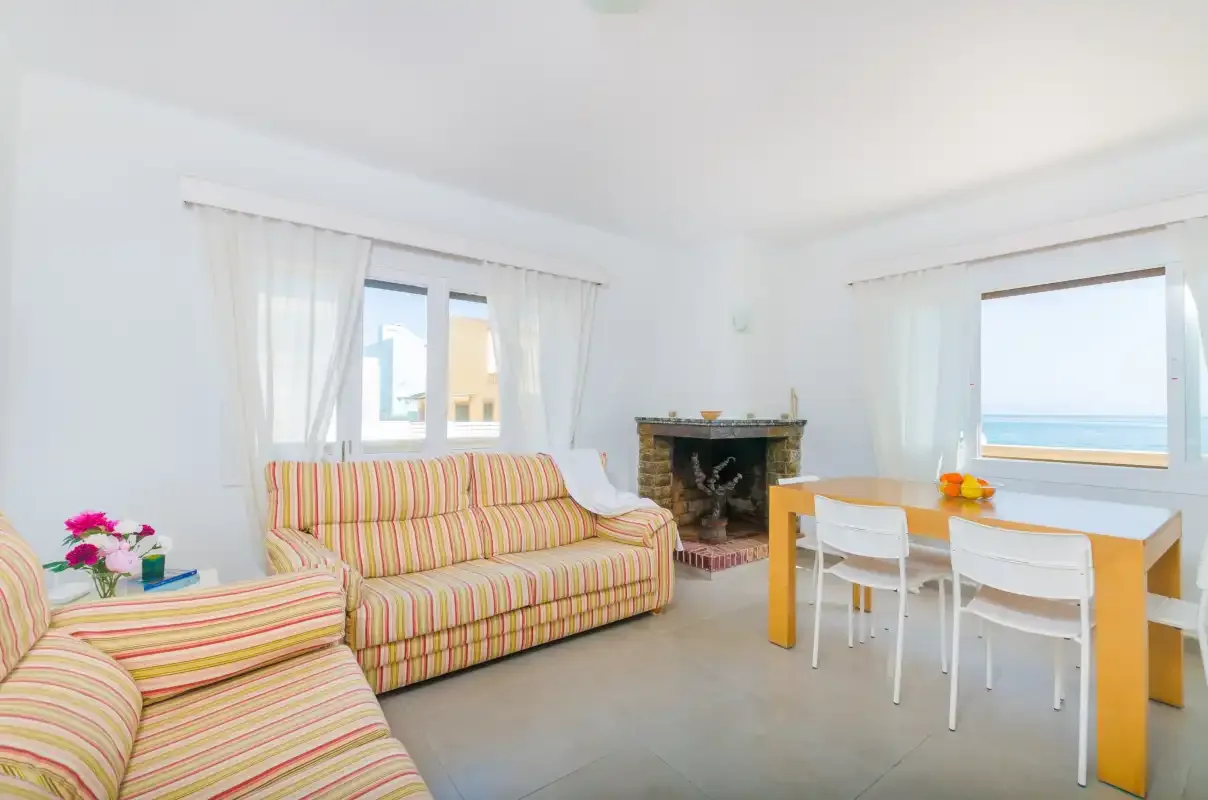 A bright living and dining area with striped seating and a table beside the window.