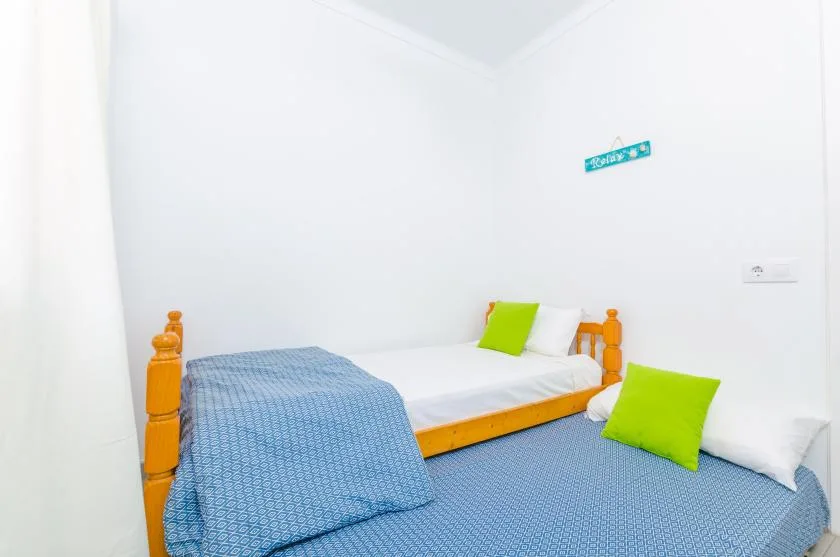 A bright bedroom with a wooden bed and blue bedding.