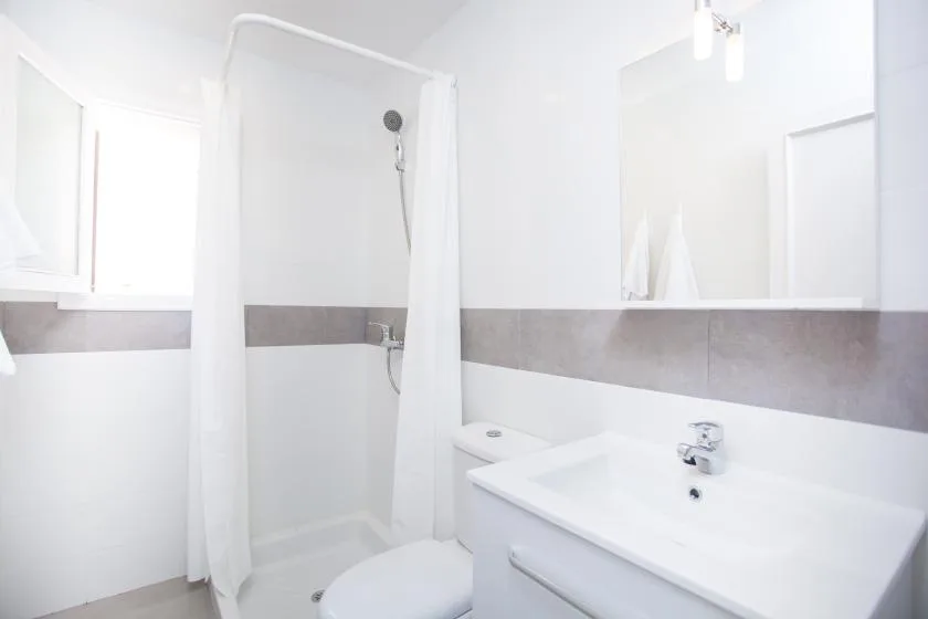 A bright bathroom with a shower, toilet, and sink.