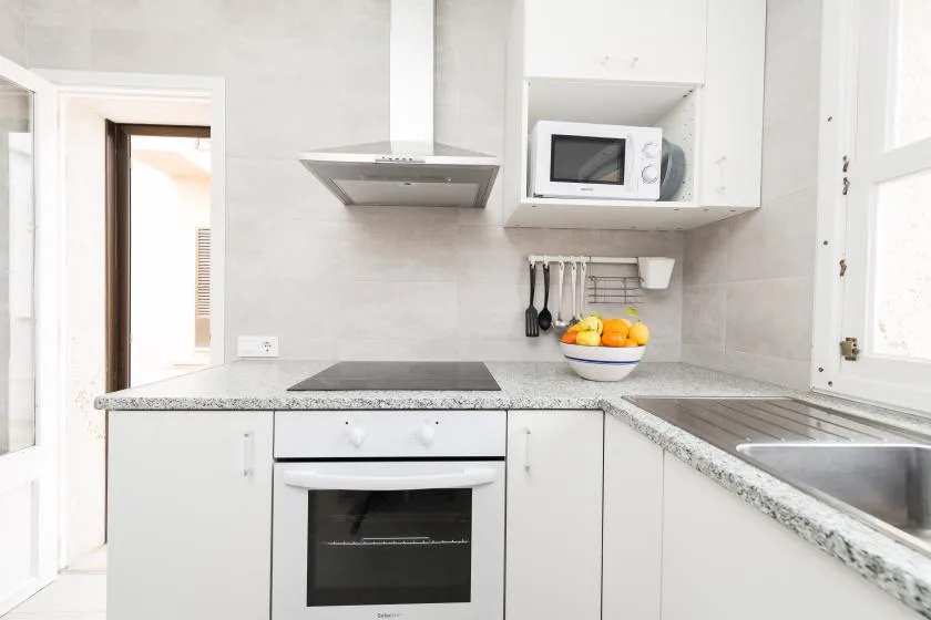 A bright kitchen with white cabinets, a countertop, and a built-in oven.