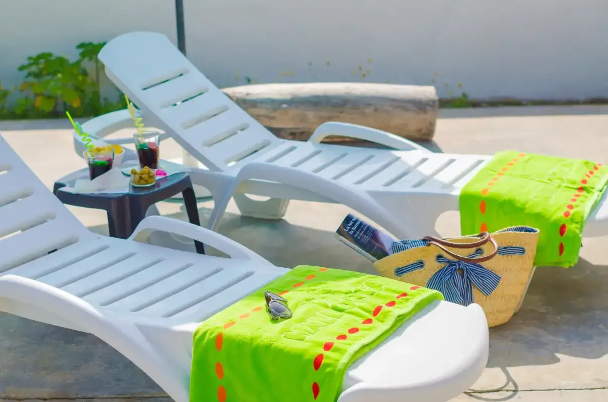 White lounge chairs with bright towels sit beside a small outdoor table.