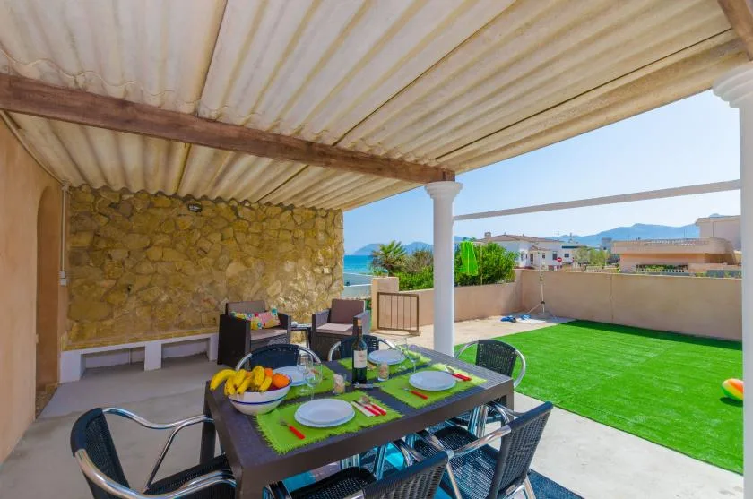 An outdoor dining area under a covered patio overlooks a green lawn.