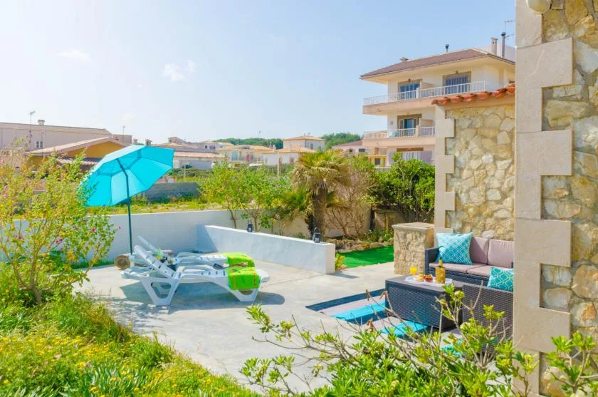Outdoor patio with seating, a turquoise umbrella, and a small pool.