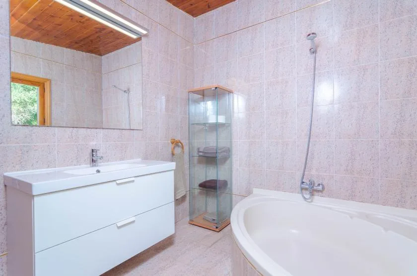 A tiled bathroom with a vanity, a bathtub, and a glass shower enclosure.