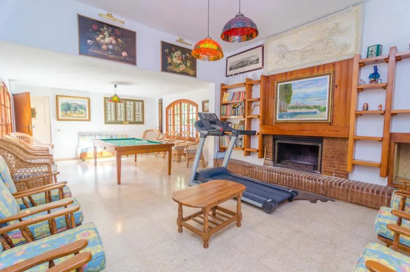 A bright living room with seating, a fireplace, and exercise equipment.