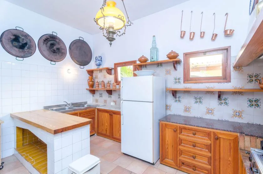 A tiled kitchen with wooden cabinets, a refrigerator, and a countertop.