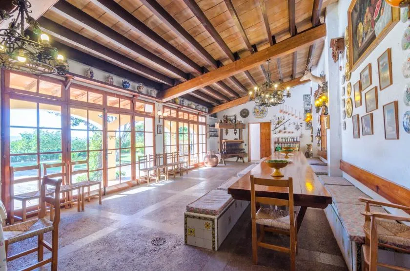 A spacious dining room with a long wooden table and large windows.