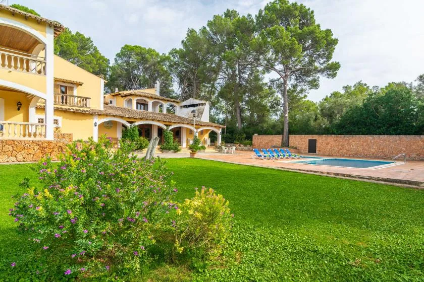 A landscaped garden and swimming pool beside a large villa.