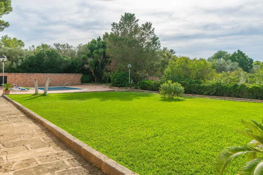 A landscaped outdoor area features a broad lawn beside a swimming pool.