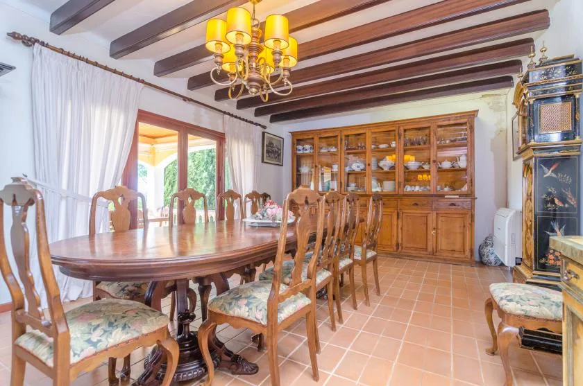 A dining room with a long wooden table and a glass-front cabinet.