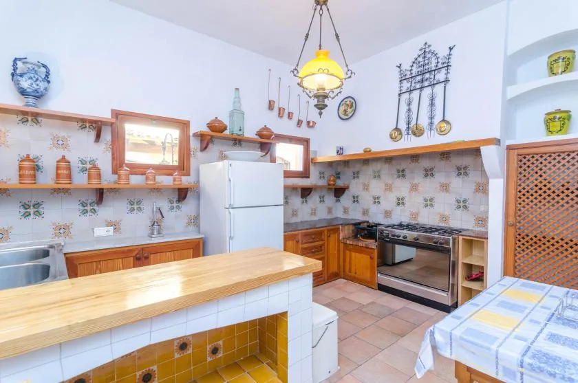 A bright kitchen with a refrigerator, tiled backsplash, and central counter.