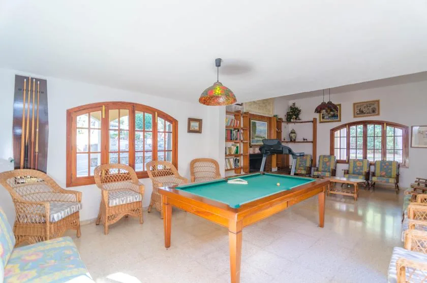 A billiards room with a green-felt pool table and wicker seating.