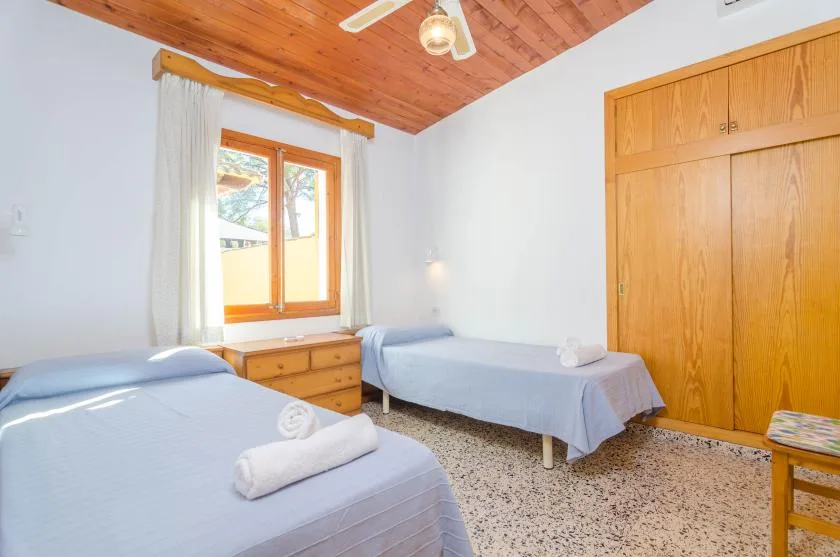 A bedroom with two beds, a window, and a wooden wardrobe.