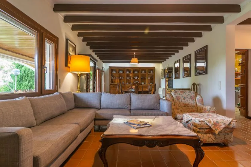 A living room with a sectional sofa, coffee table, and exposed ceiling beams.