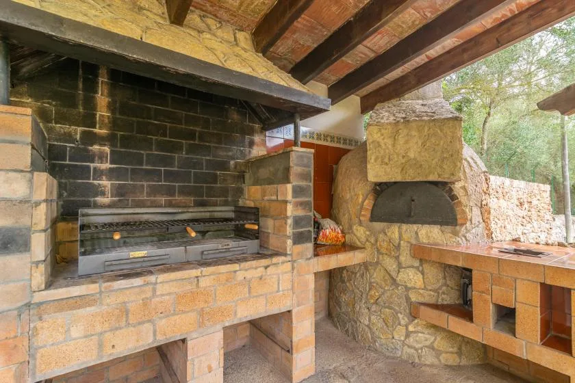 A covered outdoor cooking area with a built-in grill and stone oven.