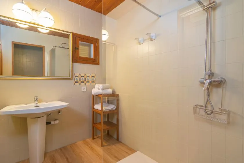 A tiled bathroom with a pedestal sink, mirror, and shower.