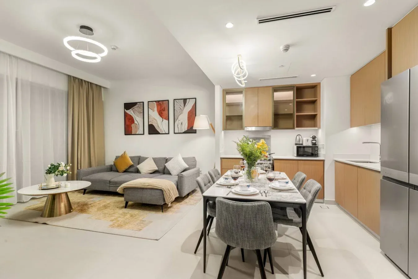 Un luminoso espacio de sala y comedor con cocina y una mesa preparada para comer.