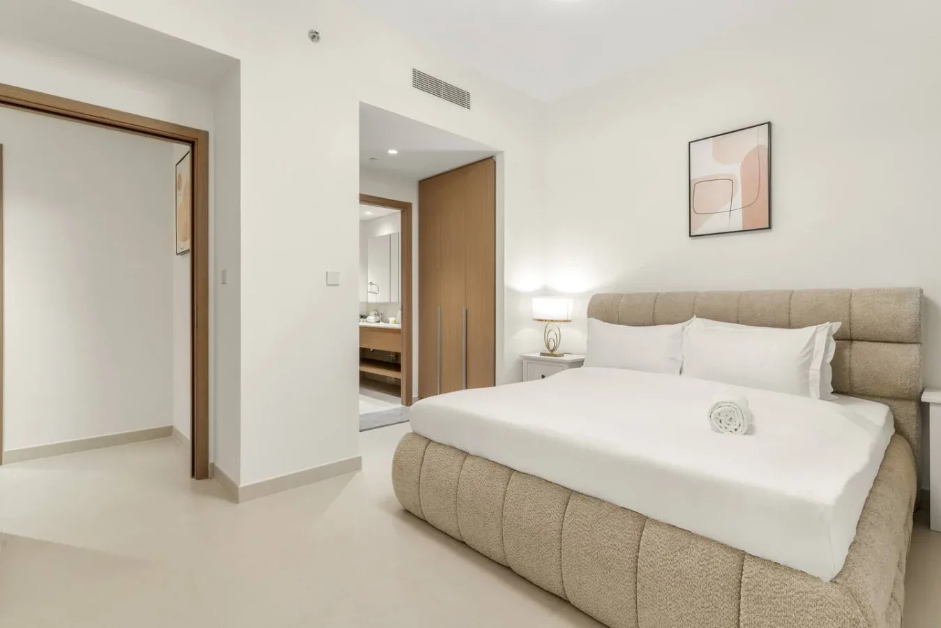 Un dormitorio con una cama grande, una mesa de noche y un cuadro en la pared.