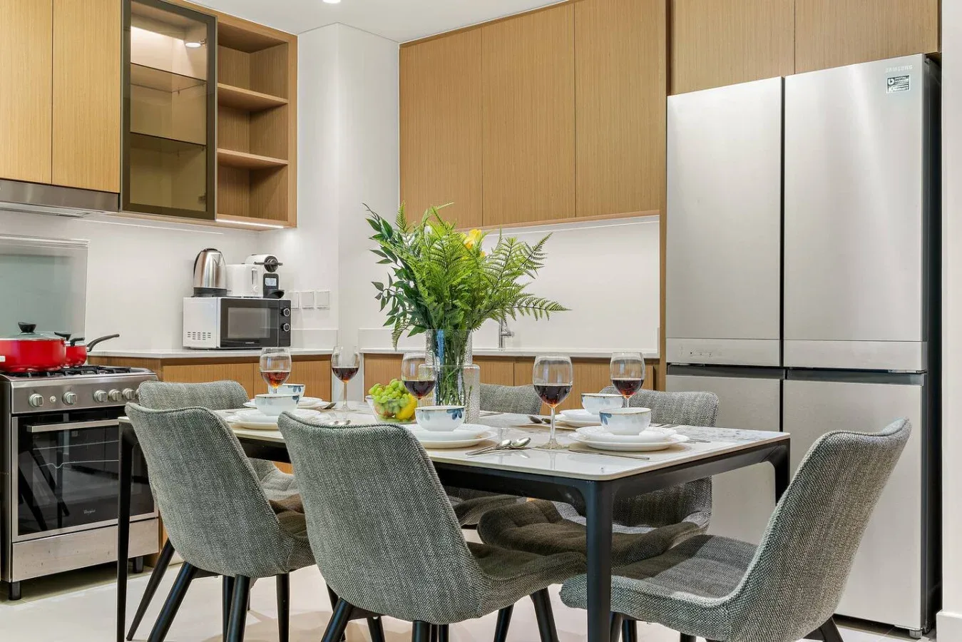Una mesa de comedor con platos está junto a una cocina moderna con armarios de madera.