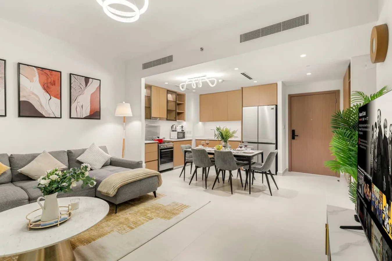 Una luminosa sala de estar y comedor con asientos grises y una cocina abierta.